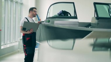 Dizüstü bilgisayarı olan erkek işçi motorlu tekne durumunu kontrol ediyor.
