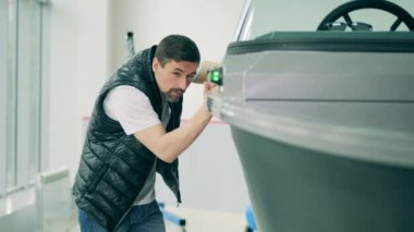 Bir adam galeride motorlu tekne gözlüyor.
