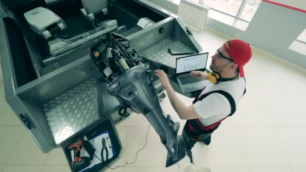 Специалист мастерской занимается ремонтом двигателей катеров — стоковое видео