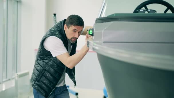 Un homme observe un bateau à moteur dans le showroom — Video