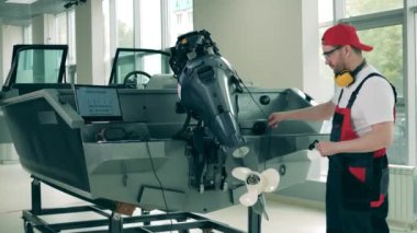 Görevli bir teknenin motorunu kontrol ediyor ve tamir ediyor.