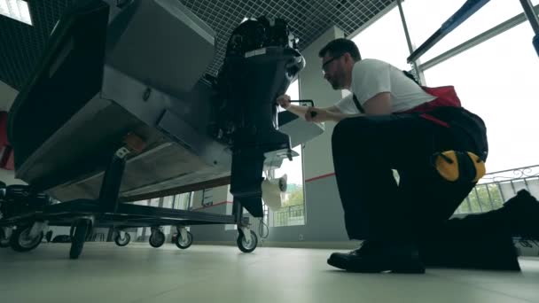 Работник чинит лодочные моторы в мастерской — стоковое видео