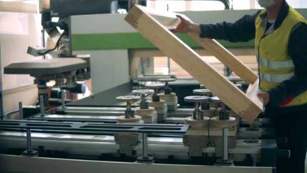 Pracownik fabryki nakłada drewnianą ramę na maszynę. — Wideo stockowe