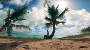 Okyanus kıyısında palmiye ağaçları ve rahat bir bayan.