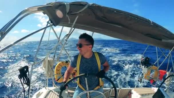 Sonriente hombre está navegando un velero a través de las aguas del mar — Vídeos de Stock