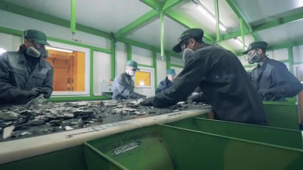 Recycling center arbeiders sorteren afval op een transportband. — Stockvideo