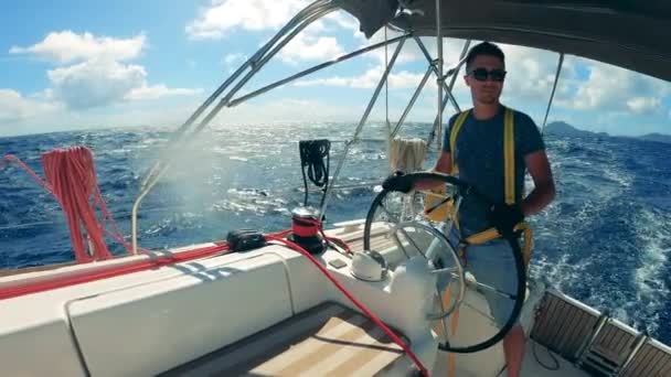 Um homem está governando o iate através das águas do oceano azul — Vídeo de Stock