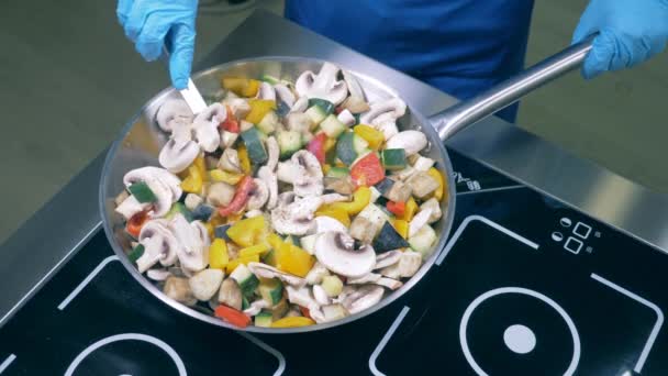Un cocinero usa espátula para remover verduras y setas en una sartén. — Vídeos de Stock