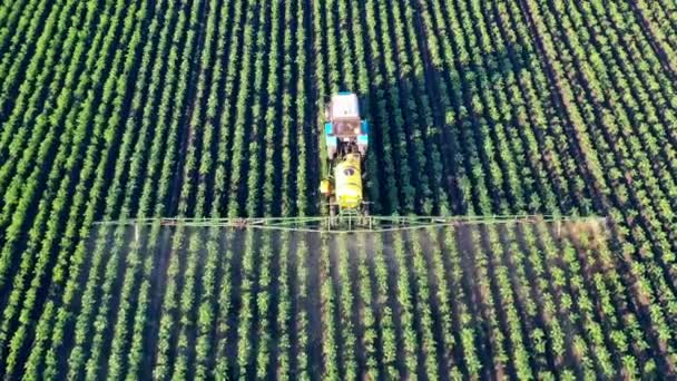 Vista superior de una máquina industrial fertilizando un campo verde. Productos químicos utilizados por los tractores agrícolas. — Vídeo de stock