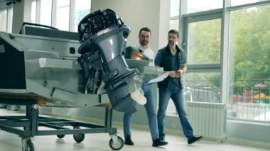 İki adam galeride bir tekne almayı tartışıyorlar.