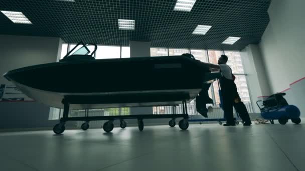 Maintenance man is fixing a speedboat in the showroom — Stock Video