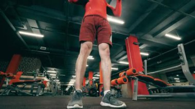 Sporcu spor salonunda dambıllarla şınav çekiyor.