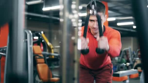 Hombre atleta está haciendo un ejercicio para los brazos con una máquina de fitness — Vídeos de Stock