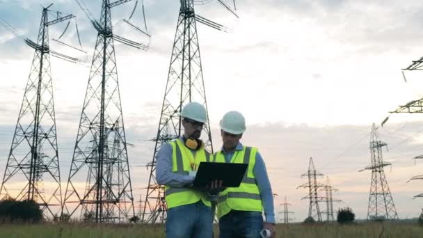 Powermen diskuterar ett projekt bredvid eltornen — Stockvideo