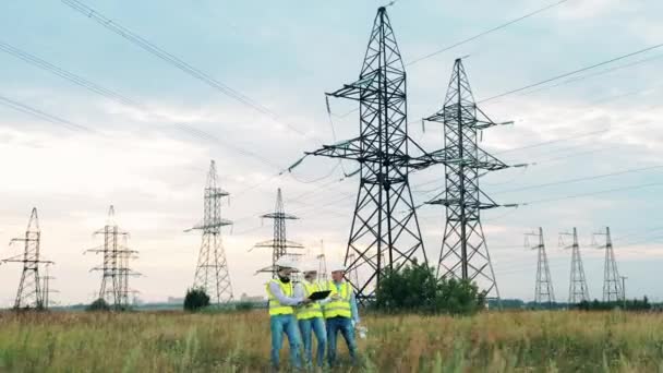 Energispecialister promenerar längs området med eltorn. Enastående ingenjörer inspekterar en kraftledning. — Stockvideo