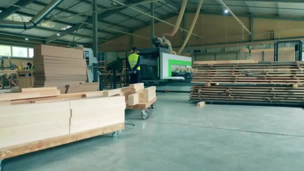 El hombre en uniforme trabaja con la máquina de la fábrica, procesando madera. — Vídeo de stock