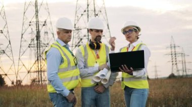 Planları ve dizüstü bilgisayarı olan enerji uzmanları konuşuyor.