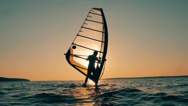 Un hombre está navegando en el océano al atardecer — Vídeos de Stock