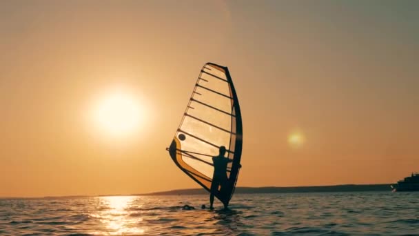 En man seglar över havet på en vindsurfingbräda. — Stockvideo