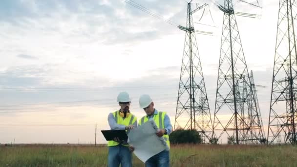 Área com torres de transmissão e dois powermen discutindo planos — Vídeo de Stock