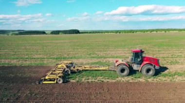 Toprağı süren bir traktörün hava görüntüsü.