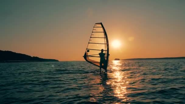 Sailboarder está atravessando o oceano ao pôr do sol — Vídeo de Stock
