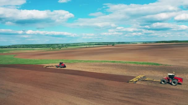 Rote Maschinen bereiten Erde für die Sau auf einem Feld vor. — Stockvideo