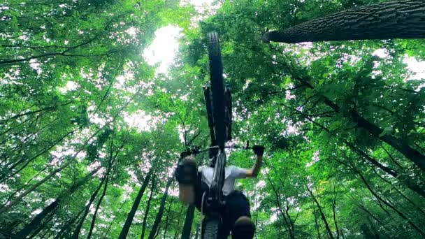 Nadeel van een man die op een fiets springt in het bos — Stockvideo