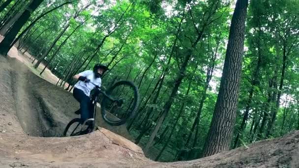 Floresta rampas e um ciclista fazendo sujeira pulando sobre eles — Vídeo de Stock