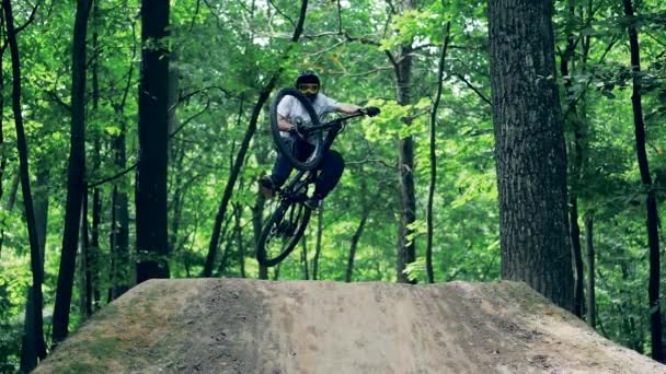 Trage beweging van een fietser die over een natuurlijke helling springt — Stockvideo