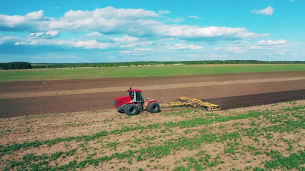 赤いトラクターは耕された土地に種を蒔く. — ストック動画