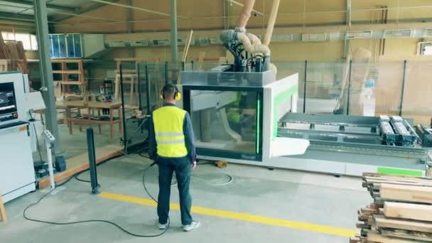 Fabrieksarbeider observeert een industriële machine die hout verwerkt — Stockvideo