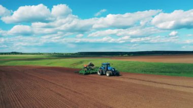 Bir traktör tarlada sürüyor, tohum ekiyor..