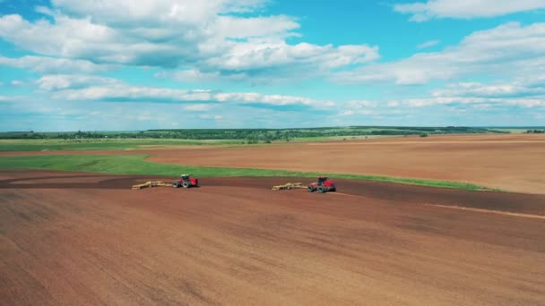 Los tractores trabajan en un campo, preparando el suelo para la plantación. — Vídeos de Stock