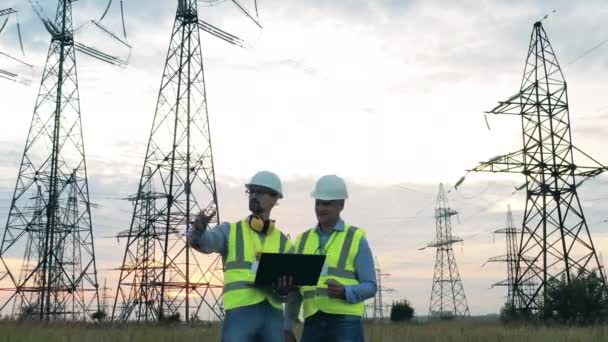 Energetica specialisten praten naast machtsmasten — Stockvideo