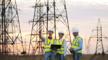 Güç mühendisleri gün batımında sahada bir tartışma yapıyorlar. Enerji tasarrufu, enerji verimliliği kavramı.