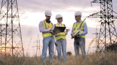 İletişim direkleri ve yanlarında konuşan bir grup mühendis.