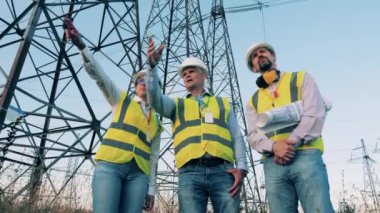 Enerji tasarrufu, enerji verimliliği kavramı. Uzmanlar elektrik nakil hatlarının yanında konuşuyorlar.