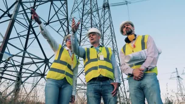 Energy saving, energy efficiency concept. Specialists are talking next to electricity transmission lines — Stock Video