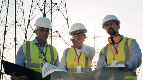 Gruppe von Ingenieuren diskutiert Anlagen in der Nähe von Strommasten — Stockvideo