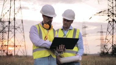 Bilgisayarlı iki güçlü adam açık havada bir projeyi tartışıyorlar.