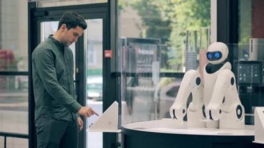 Bir adam kahve sipariş ediyor ve bir robot ona servis yapıyor.