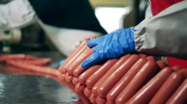 Fabrika işçileri taşıyıcıda sosis paketliyor..