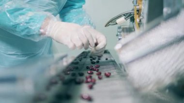 İlaç firması antivirüs üretiyor. Sıhhiyeci ışınlayıcı boyunca ilerleyen hapları inceliyor.