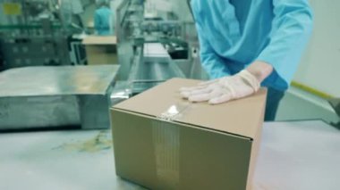 Kadın eczacı kutu paketlemek için koli bandı kullanıyor.
