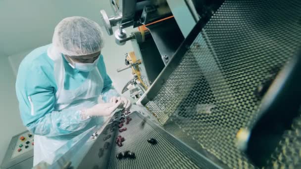 Работник фабрики внимательно изучает свежие таблетки — стоковое видео