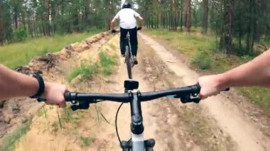 İki adam orman yolunda BMX sürüyor.