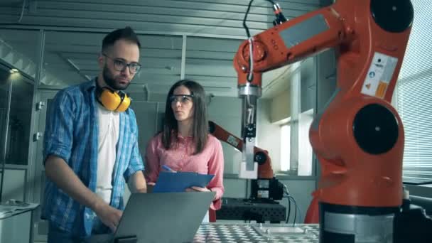 Сучасна наукова лабораторія. Жінка і чоловік контролюють роботизовану руку в лабораторії . — стокове відео