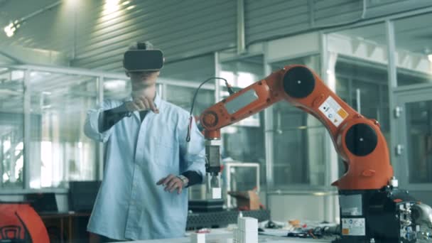 Man uses VR glasses to control robotic arm at factory. — Stock Video