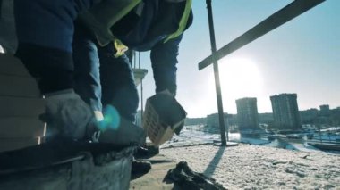 İnşaat işçisi tuğla ve çimentodan bir duvar inşa ediyor.